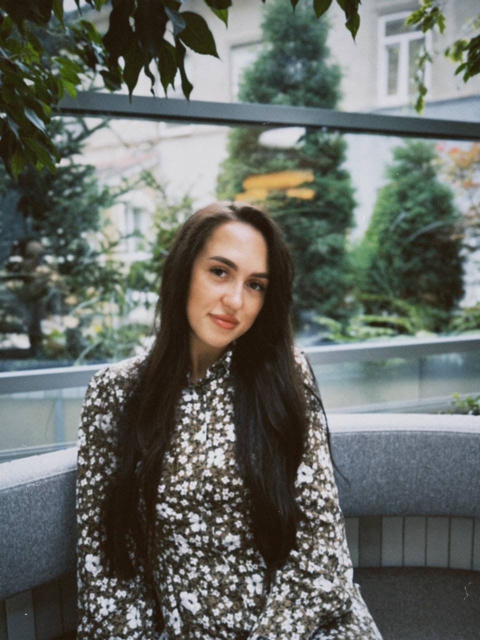 Woman sitting outdoors with greenery in the background